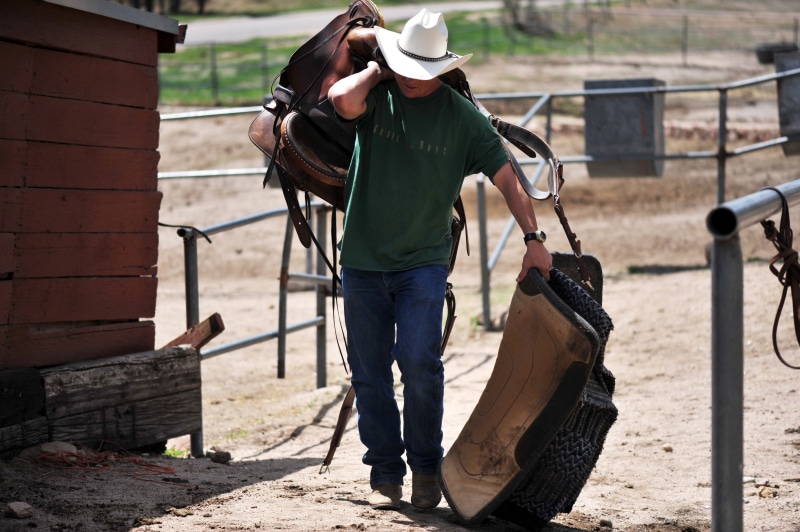 one person, front view, horse, green, real people, brown, clothing, man, symbol, full length, young, shirt, usa, crew, day, hat, standing, people, western