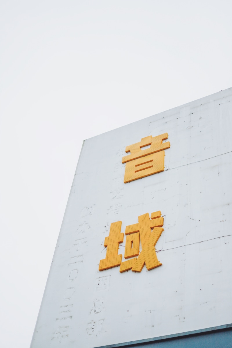 word, logo, low angle view, symbol, yellow, hotel, concrete, white color, alphabet, text, western script, white, outdoors, house, town, copy space, communication