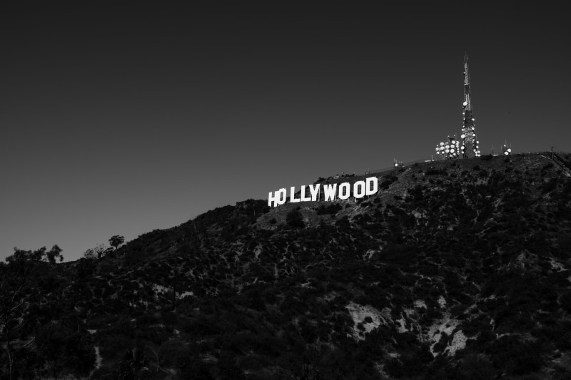 photography, signage, outdoors, highland, hollywood, clear sky, architecture, sky, black and white, western script, low angle view, tree, building exterior