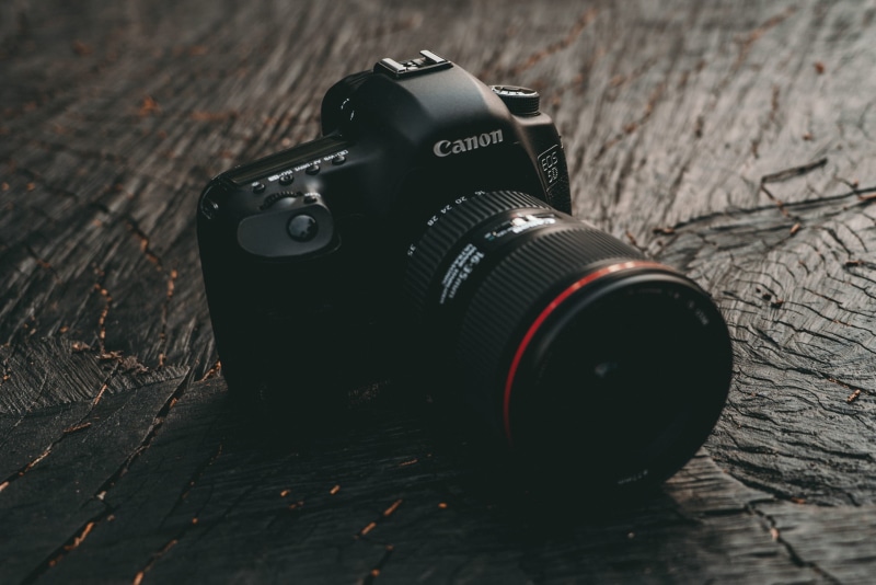 personal accessory, photographer, camera, lens - optical instrument, black color, dslr, day, equipment, camera - photographic equipment, table, slr camera