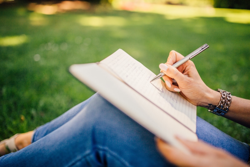 grass, human hand, woman, leisure activity, book, girl, outdoors, studying, young adult, one person, park, day, lifestyles, writer, publication, writing