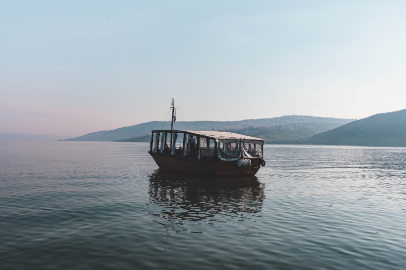 barge, nautical vessel, outdoors, mode of transportation, sea of galilee, no people, clear sky, person, mountain, waterfront, sea, watercraft, nature, tiberius