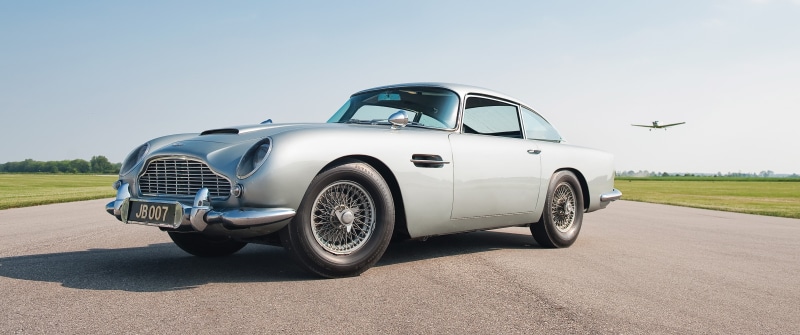 motor vehicle, transportation, clear sky, driving, wheel, day, sky, stationary, road, nature, mode of transportation, travel, Aston Martin DB5, tire, motion