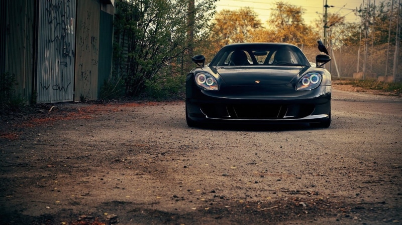 mode of transportation, black cars, transportation, car, no people, stationary, city, outdoors, plant, road, gravel, building exterior, motor vehicle, parking