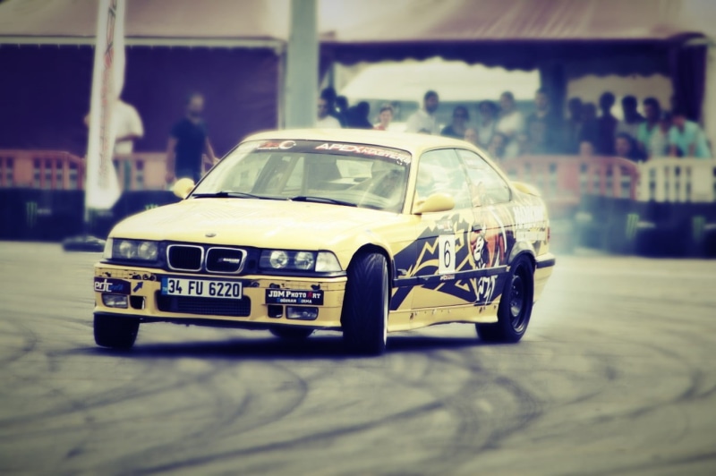 selective focus, BMW E36, toy car, land vehicle, motor vehicle, architecture, BMW, toy, sedan, drift, taxi, focus on foreground, close-up, yellow, indoors