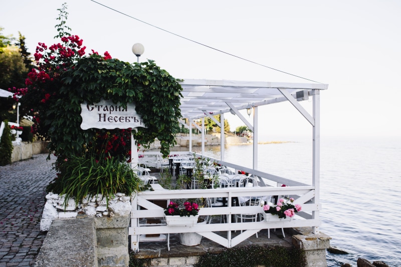 table, water, seat, building exterior, Europe, Restaurants, text, western script, sky, potted plant, street, travel, old, restaurant, architecture, day