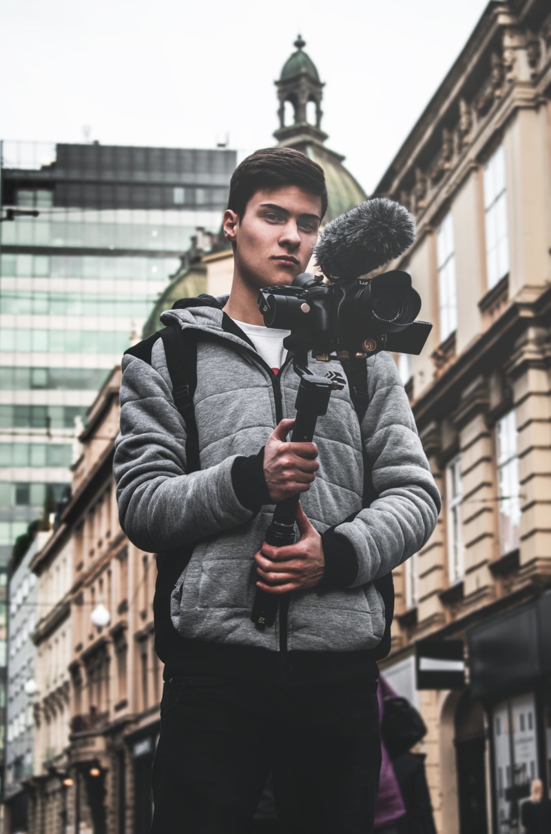 photographer, man, tower, outdoors, near, technology, apparel, portrait, street, architecture, face, electronics, young men, clothing, human, camera, photo