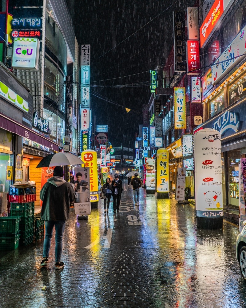 tourists, seoul, building exterior, person, real people, people, holding, neon sign, weather, black, city, town, wet, rain, sign, nightlife, restaurant