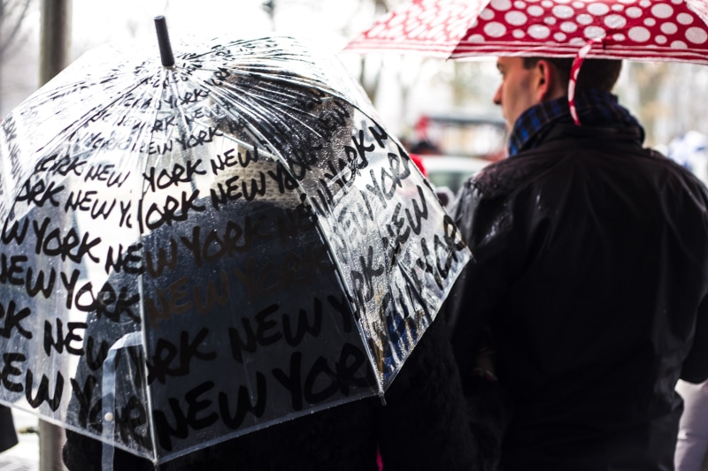 communication, daytime, wearing, 5K, rear view, city, clear, waist up, rain, text, focus on foreground, security, jacket, red, real people, man, near