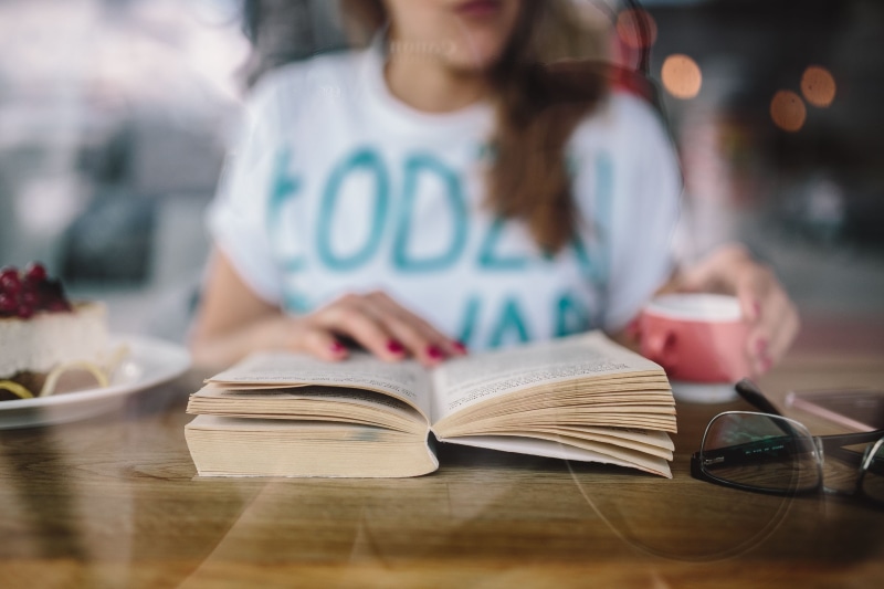 only women, focus on foreground, publication, one person, sitting, caucasian, education, young adult, Woman reading, cafe, woman, one woman only, table