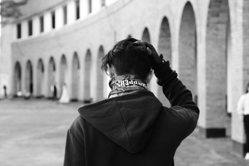 rear view, photography, incidental people, focus on foreground, 4K, the past, built structure, arch, grayscale, architectural column, one person, hood - clothing