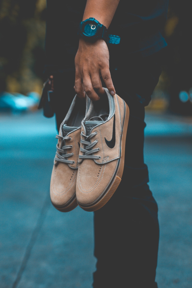 person, logo, midsection, shoe, human body part, pair, focus, leisure activity, real people, lifestyles, shoes, man, standing, low section, nike, focus on foreground