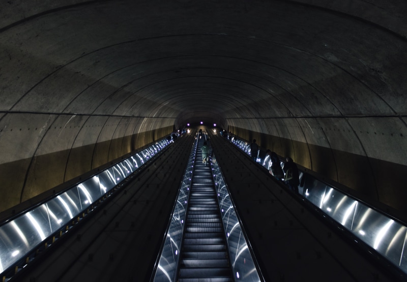 staircase, real people, diminishing perspective, metro, arch, railing, illuminated, low angle view, technology, direction, 5K, architecture, ceiling, one person