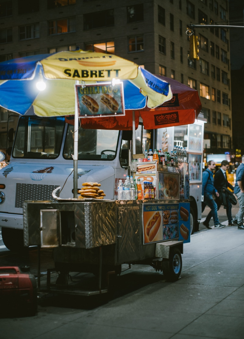 people, communication, manhattan, hot dog, cart, van, city, motor vehicle, light, road, kiosk, street, transportation, human, glow, new york, day, incidental people