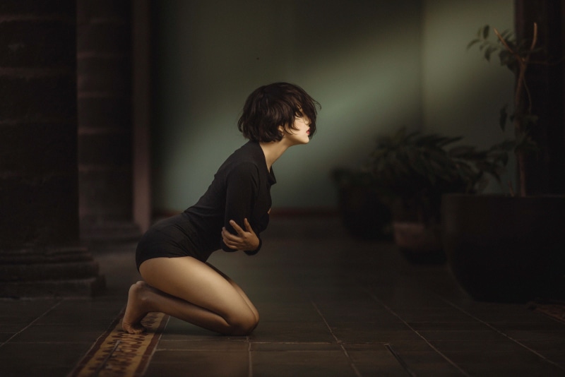 hairstyle, nikon, gray, floor, emotion, beautiful woman, inside, full length, pose, woman, dim, profile view, black color, portrait, boke, indoors, lit
