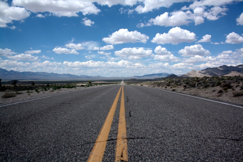 road marking, direction, horizon, symbol, double yellow line, arid climate, nature, vanishing point, road, environment, sign, mountain range, empty road