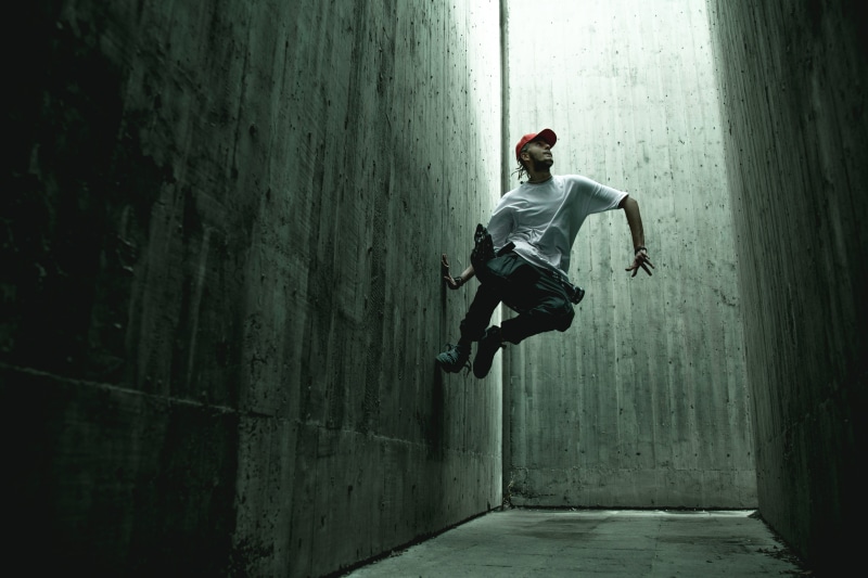 one person, shoe, shirt, leisure activity, footwear, white, leisure activities, human, concrete, mid-air, wall, architecture, outdoors, apparel, tunnel