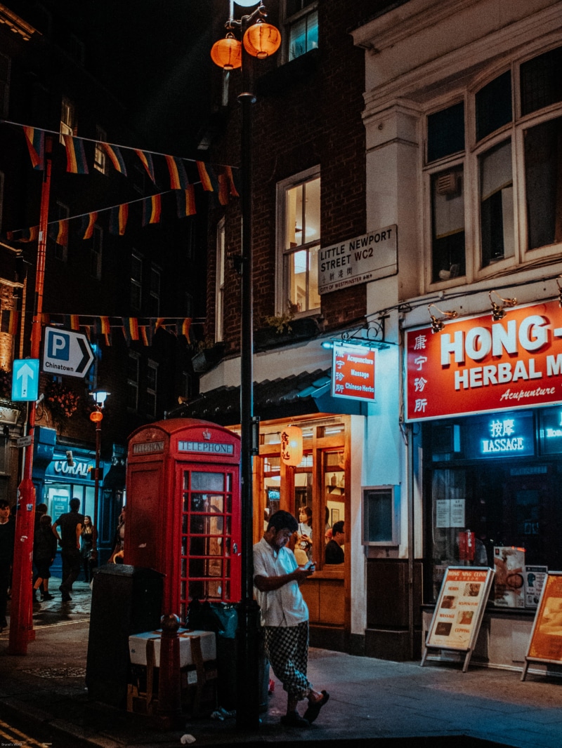 building exterior, payphone, shop, adult, leaning, urban, brown, building, store, chinatown, real people, post, man, communication, night, lifestyles, metal