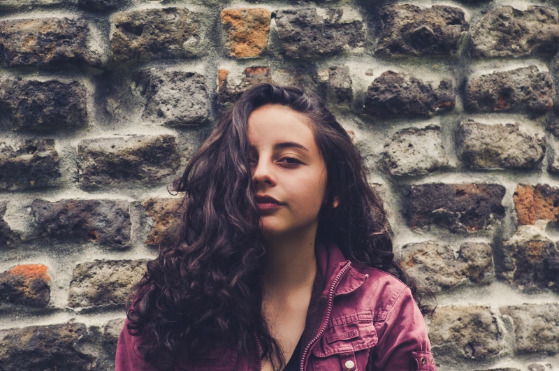 front view, hairstyle, happy, open air, adult, beautiful, wall, casual Clothing, wall - Building Feature, one Woman Only, females, jacket, birds, wings