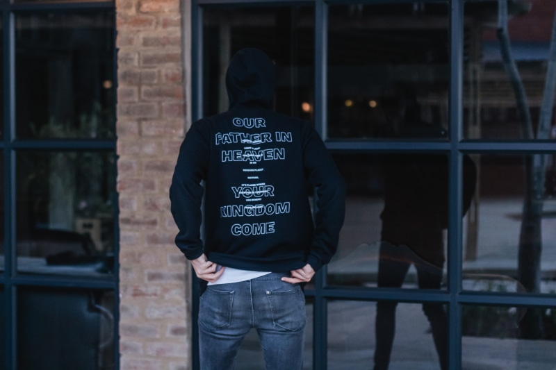 footwear, sleeve, building exterior, window, jeans, door, built structure, text, human, lifestyles, sitting, hat, western script, 5K, clothing, looking