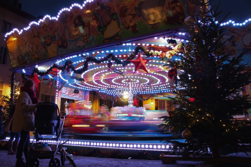 outdoors, lighting, person, woman, street, holiday, carousel, christmas tree, manège, amusement park ride, plant, beside, theme park, standing, overcoat