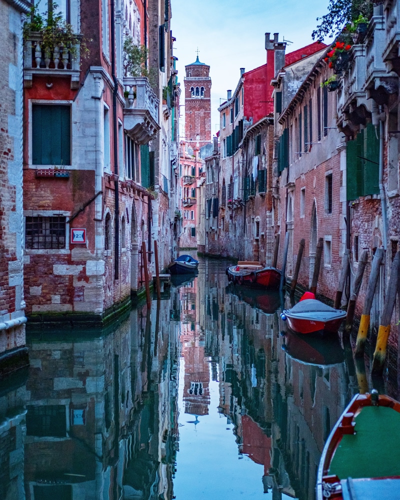 no people, transportation, water, wooden post, moored, rowboat, brown, residential district, nautical vessel, buildings, boat, waterfront, sky, city, near