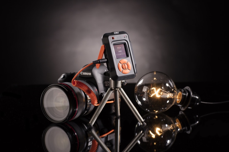 black background, old, red, photographer gear, dark, studio shot, black, refleciton, camera trigger, 4K, no people, light, filament, communication, camera device