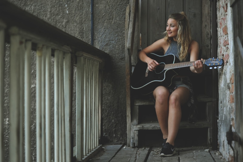 girl, indoors, day, tank, beautiful girl, blond, stringed instrument, black, lifestyles, outdoors, young adult, wearing, real people, happy, sitting, musician