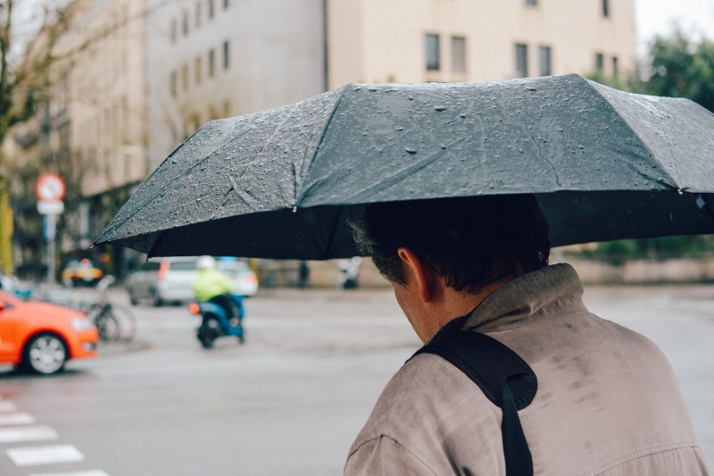 vehicles, man, building exterior, wet, adult, along, one person, city street, blurred background, rainy season, security, holding, cars, black, protection