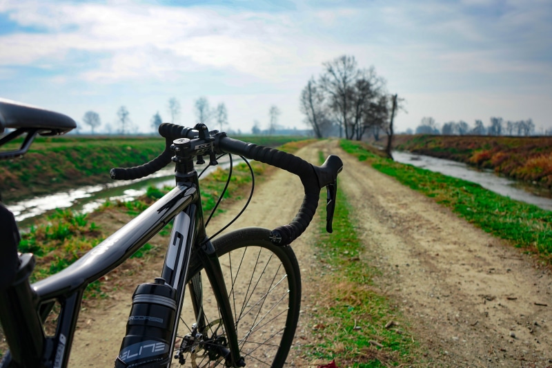 path, mode of transportation, race bike, alley, cloud - sky, bicycle, tree, dirt road, no people, gravel, day, land, straight, pathway, stationary, plant