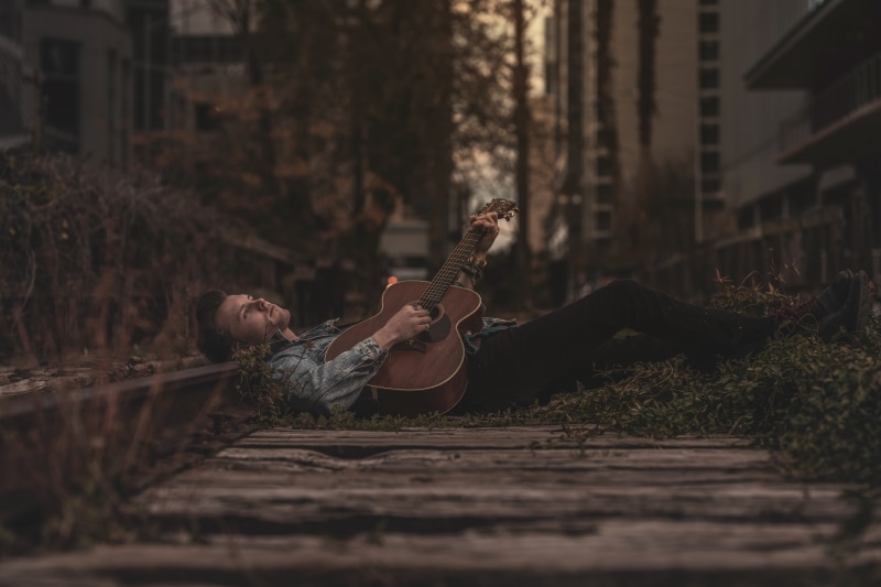 male model, young women, street, architecture, casual clothing, one person, lying, real people, pose, 8K, leisure activity, guitarist, selective focus