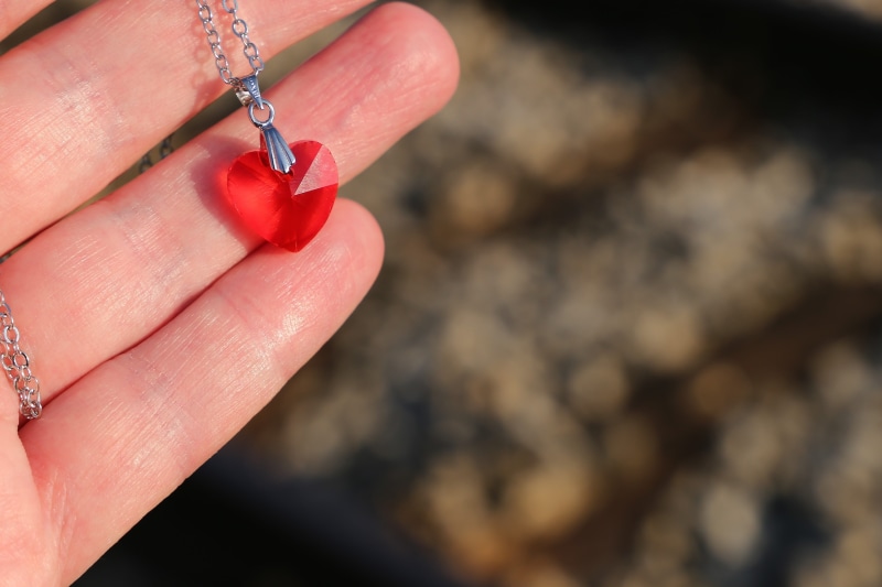 positive emotion, chain, red, focus on foreground, necklace, body part, human body part, adult, crystal, railway tracks, love symbol, unrecognizable person