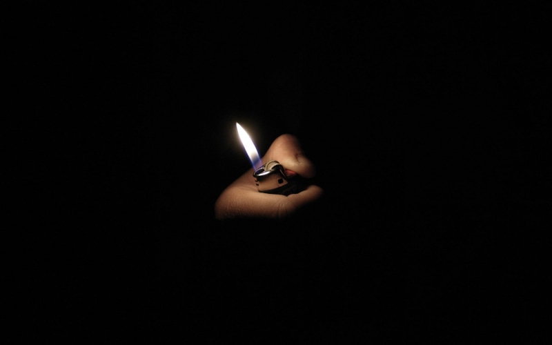 holding, cigarette lighter, human body part, flame, indoors, matchstick, black background, hands, close-up, human finger, finger, hand, 1080P, one person