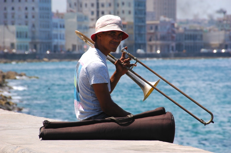 water, apparel, brass section, casual clothing, hat, boat, outdoors, focus on foreground, young adult, person, one person, flugelhorn, cuba, sunlight, horn