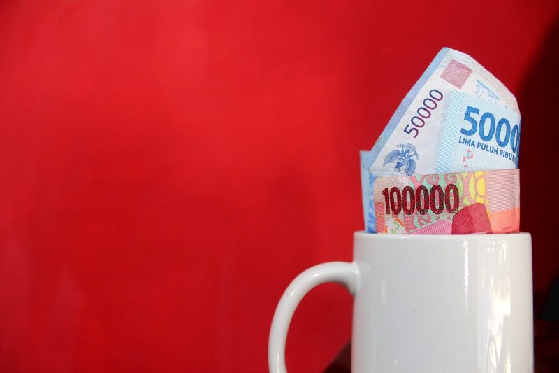 money, paper currency, cup, savings, wealth, economic, economy, currency, no people, consumerism, salary, drink, food and drink, red background, still life