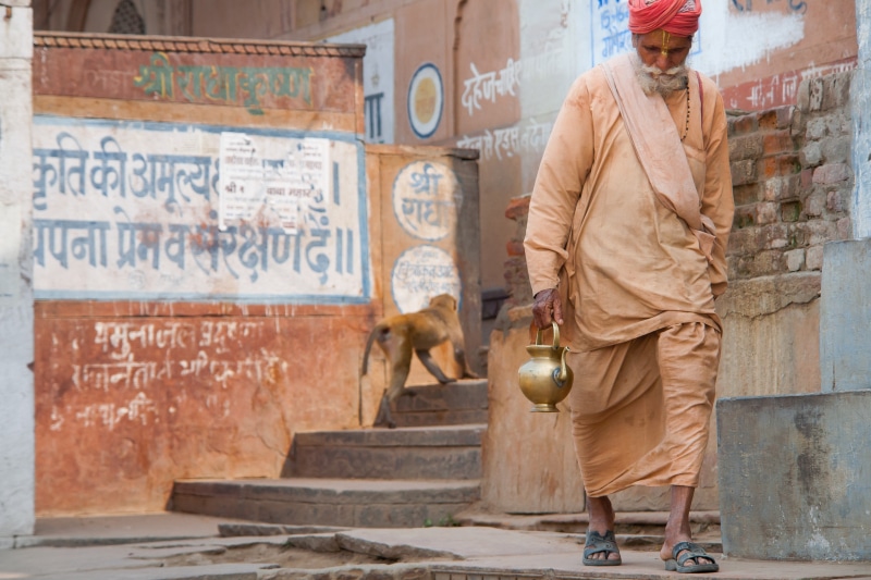 walking, building exterior, standing, front view, hinduism, lifestyles, isle, outdoors, clothing, building, holding, built structure, city, travel, man