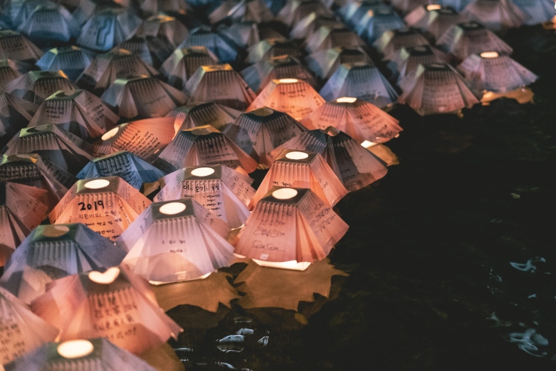 paper, text, large group of objects, nature, communication, place of worship, lanterns, lantern, orange, day, religion, abundance, floating, built structure