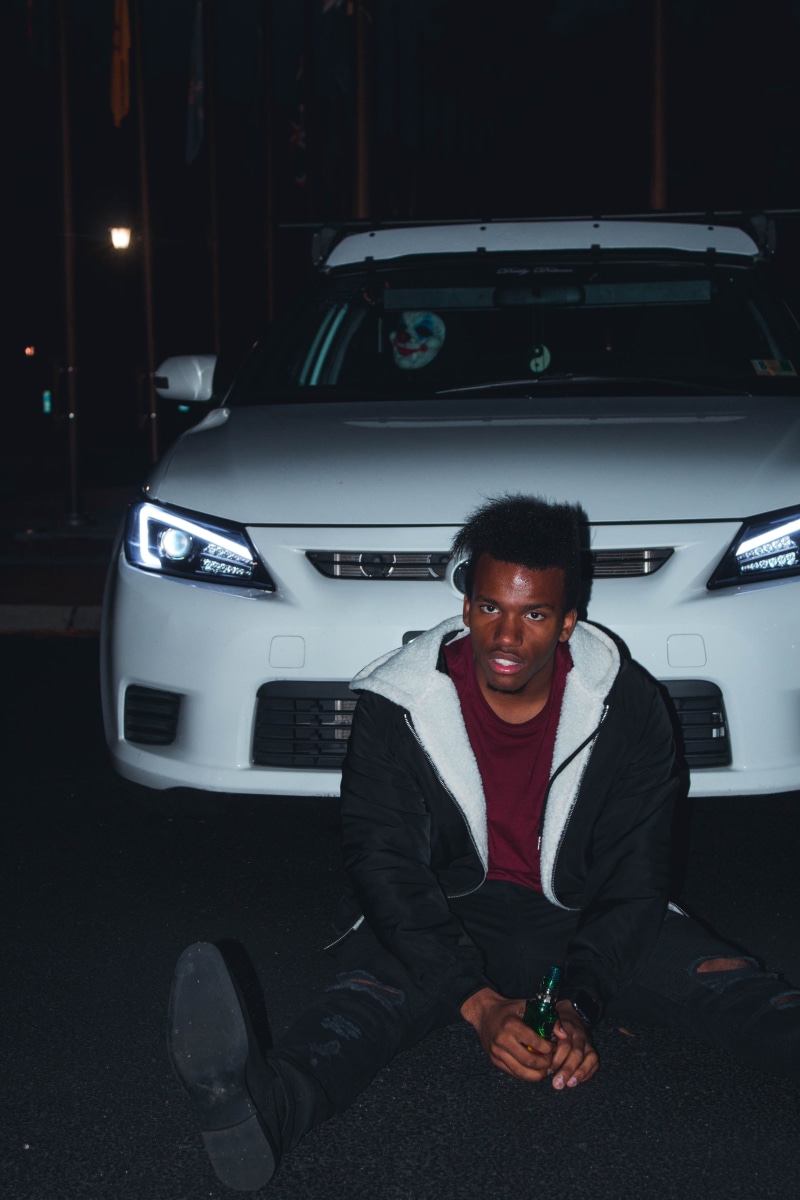 photoshoot, land vehicle, vape, mask, sitting, eerie, white, person, one person, young adult, men, transportation, man, pose, mode of transportation, leaning
