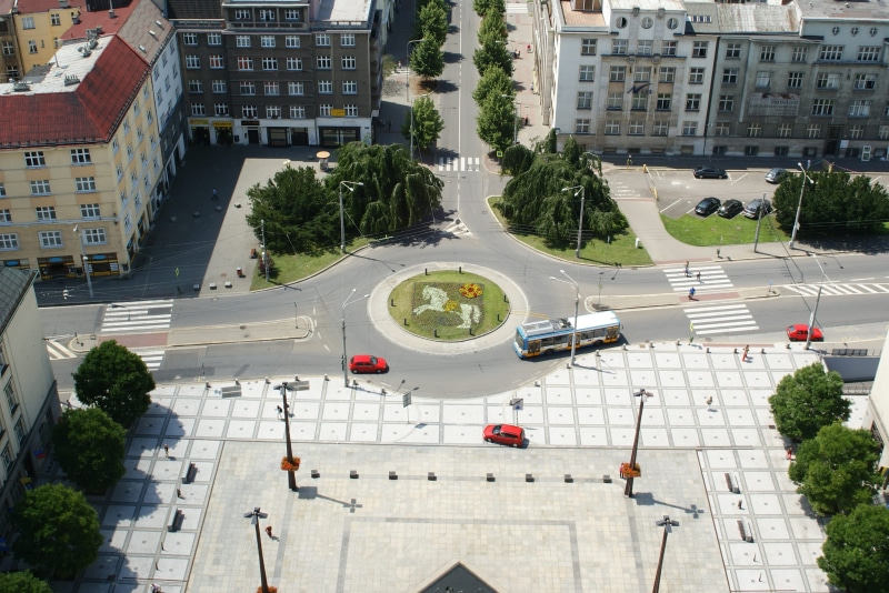 nature, built structure, tree, city, residential district, traffic circle, road, day, motor vehicle, incidental people, building, high angle view, crossroad
