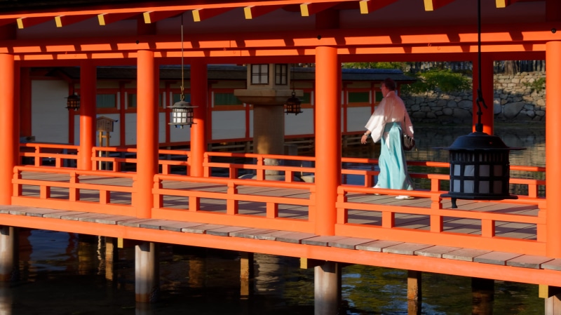 orange, adult, place of worship, casual clothing, railing, one person, japan, itsukushima, built structure, shintoism, lifestyles, shinto, belief, itsukushima shrine
