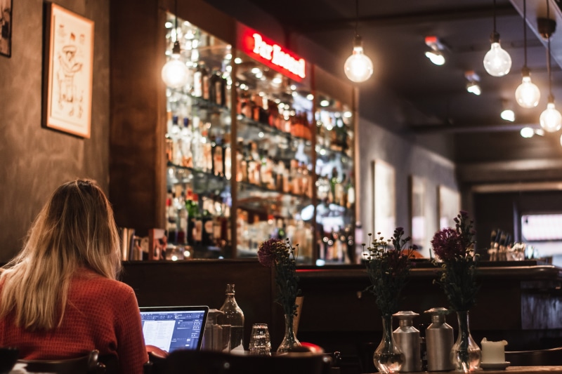 adult, business, pub, furniture, bar - drink establishment, table, pc, bottle, restaurant, glass, food and drink, liquor, wine bottle, using laptop, lifestyles