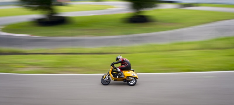 crash helmet, on the move, transportation, sport, curve, motorsport, helmet, outdoors, right curve, land vehicle, scooter, yellow, blurred motion, day