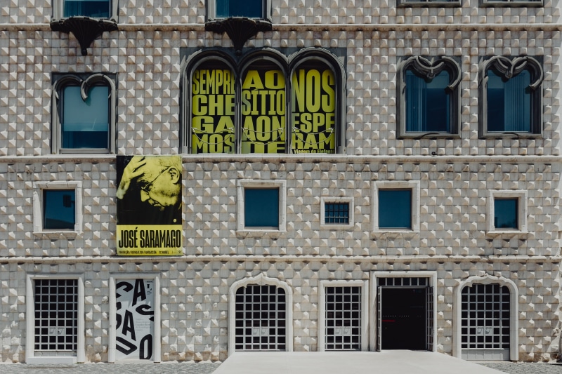 low angle view, buildings, no people, cityscape, text, glass - material, town, lisbon, day, architecture, facade, history, the past, sign, colorful, residential district