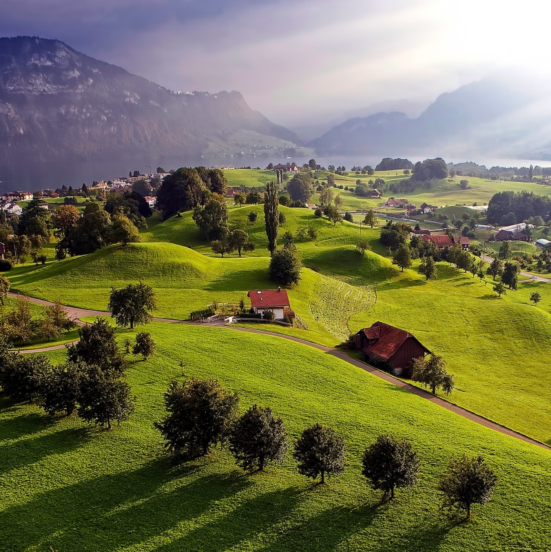 grass, landscape, sunset, tranquility, tranquil scene, alp, light, architecture, sky, balloon, farm, environment, non-urban scene, shadow, idyllic, beauty in nature