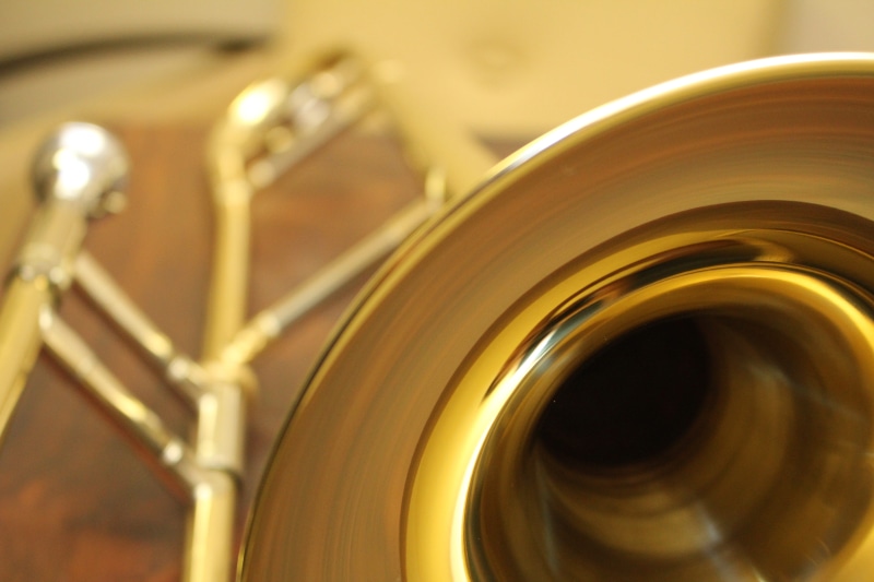 trombone image, music man, indoors, selective focus, trombone, trumpet, music store, brass, gold, wind instrument, musical instrument, arts culture and entertainment