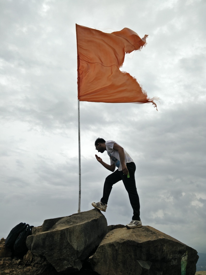standing, maharashtra, solid, rock - object, travel, sky, real people, kalavantin durg, rock, leisure activity, flag, men, nature, casual clothing, fort