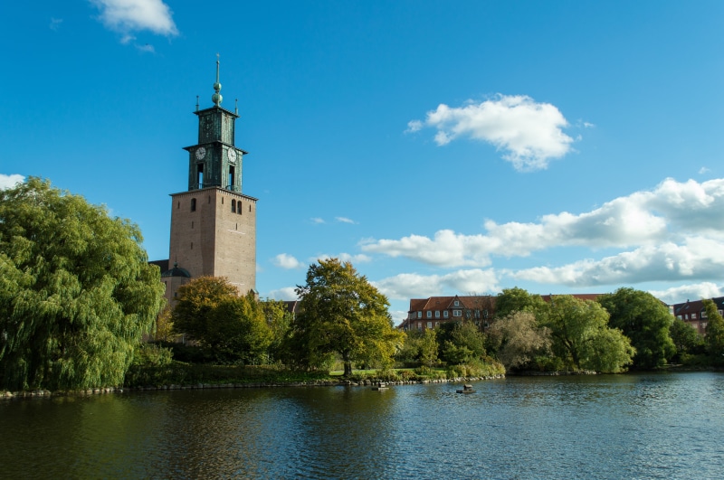 waterfront, lake, water, steeple, clock tower, built structure, sky, blue, bell tower, fort, plant, 5K, lighthouse, beacon, tree, moat, spire, cloud - sky