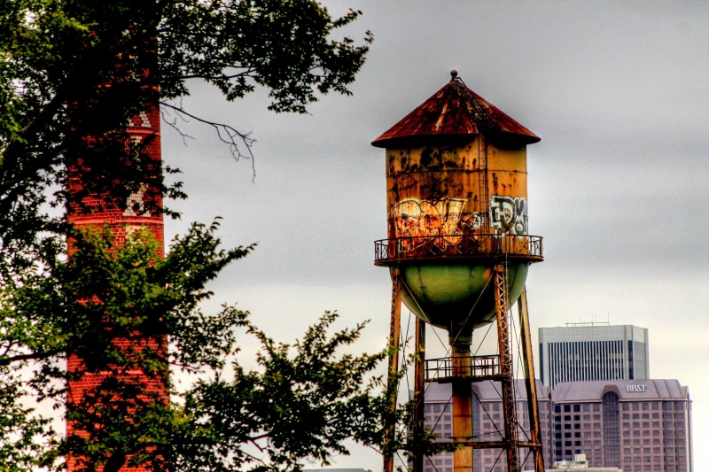 4K, water tank, building exterior, city, low angle view, growth, water, sky, skyline, graffiti, outdoors, nature, lookout tower, old, plant, built structure
