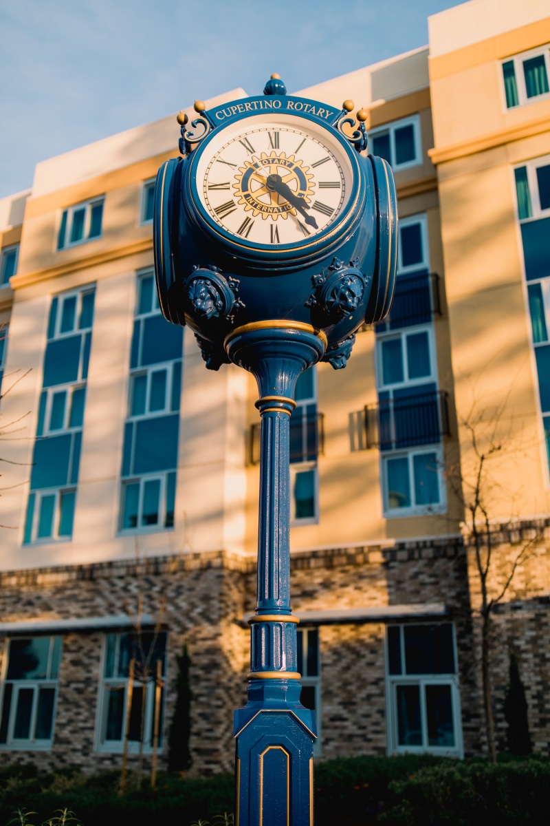 bell tower, clock, focus on foreground, city, analog clock, vehicle, built structure, coupe, no people, spire, transportation, sports car, town, urban