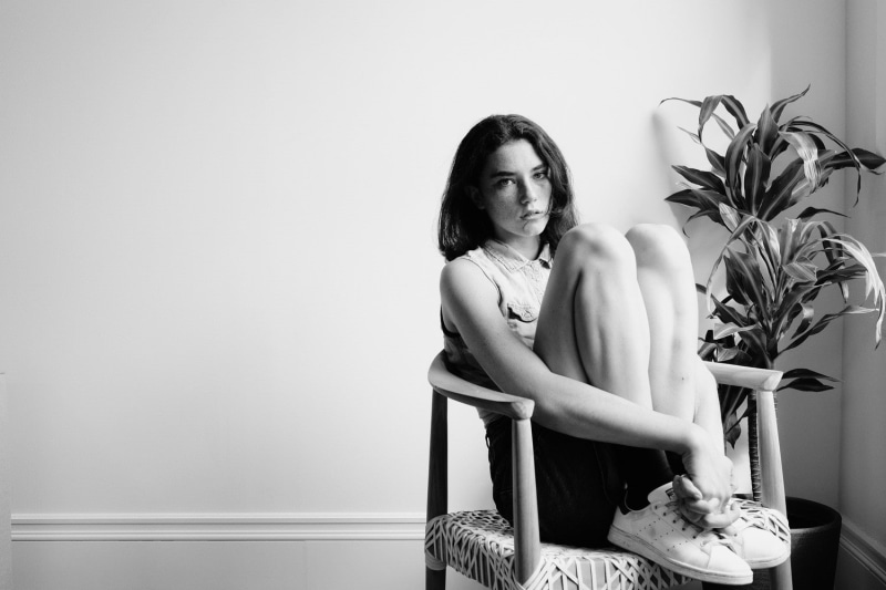 plant, legs together, young adult, adult, freckles, chair, women, front view, beautiful woman, sitting, looking, one person, wall - building feature, contemplation